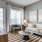 A neatly arranged living room featuring a white sofa, a pair of framed wall art pieces, a round coffee table, and with ample natural light coming in from the window
