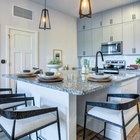 Modern kitchen with a central island, bar stools, stainless steel appliances, and a dining area at Prime in Kissimmee, FL