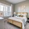A neatly arranged bedroom at Prime with a beige upholstered bed, white bedding, decorative pillows, and two white table lamps on matching nightstands.