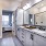 A modern bathroom featuring a double sink vanity with a granite countertop, large mirrors, and a glass-enclosed shower visible in the background